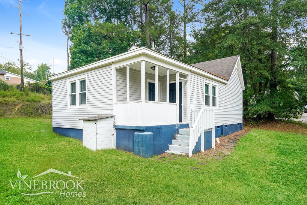 A white house with a blue stripe on the front steps is for sale.