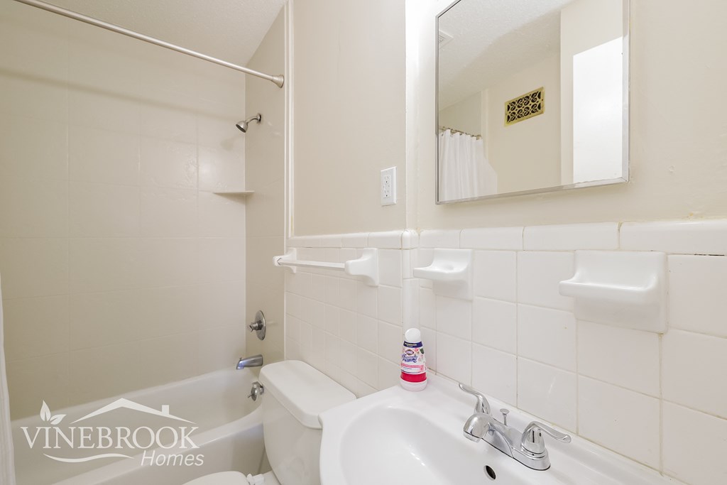 a white bathroom with a sink and a tub and a mirror