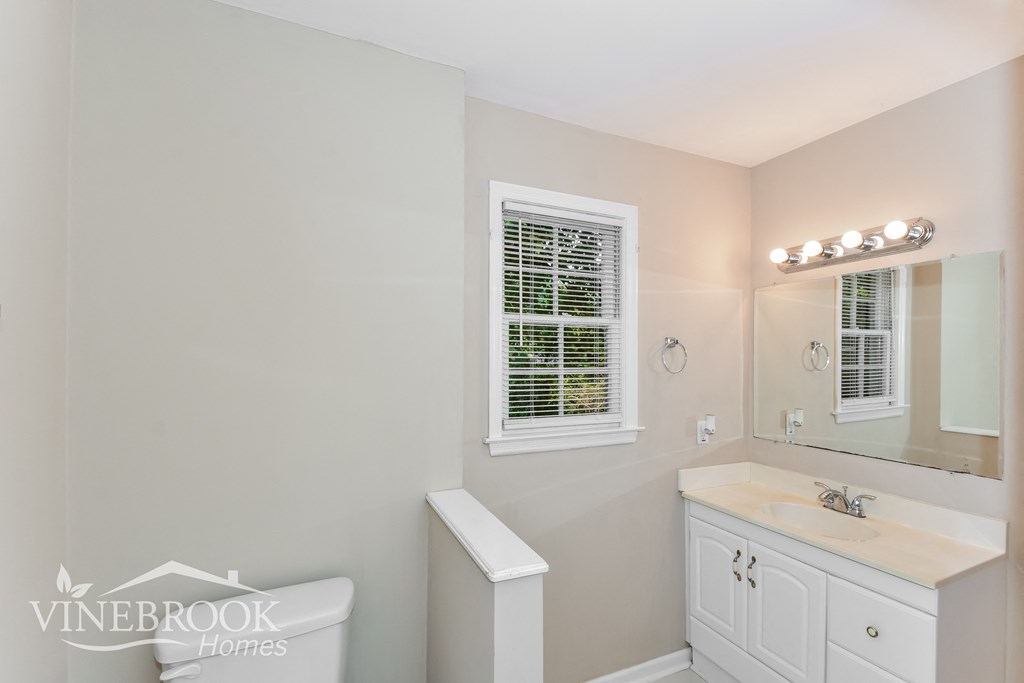 a white bathroom with a sink and toilet and a mirror