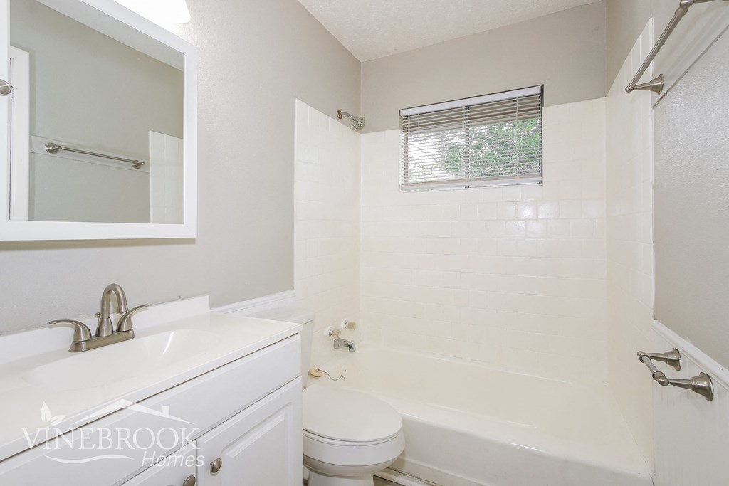 a white bathroom with a tub and a sink and a toilet