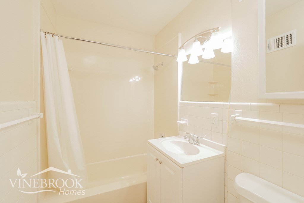 a white bathroom with a sink and a mirror and a shower