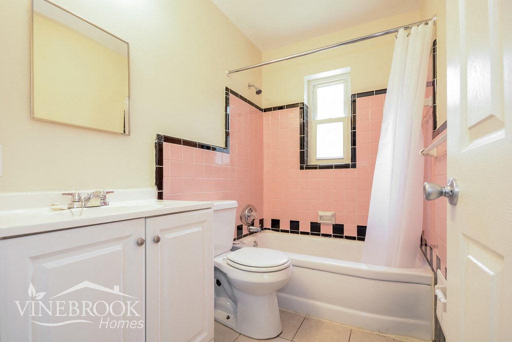 a bathroom with pink tiles and a toilet and a tub