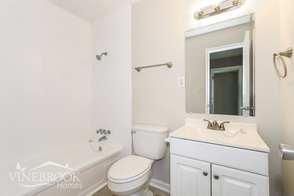 a white bathroom with a toilet sink and tub and a mirror