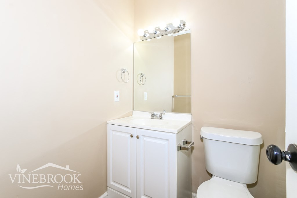 a white bathroom with a toilet sink and mirror