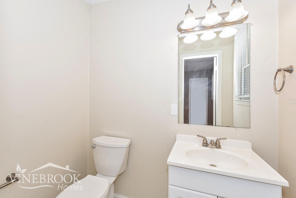 a white bathroom with a sink toilet and a mirror