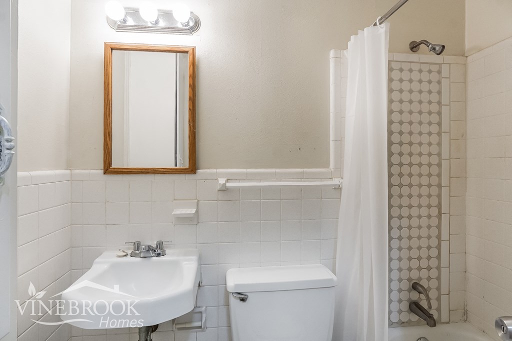 a white bathroom with a sink and a toilet and a shower