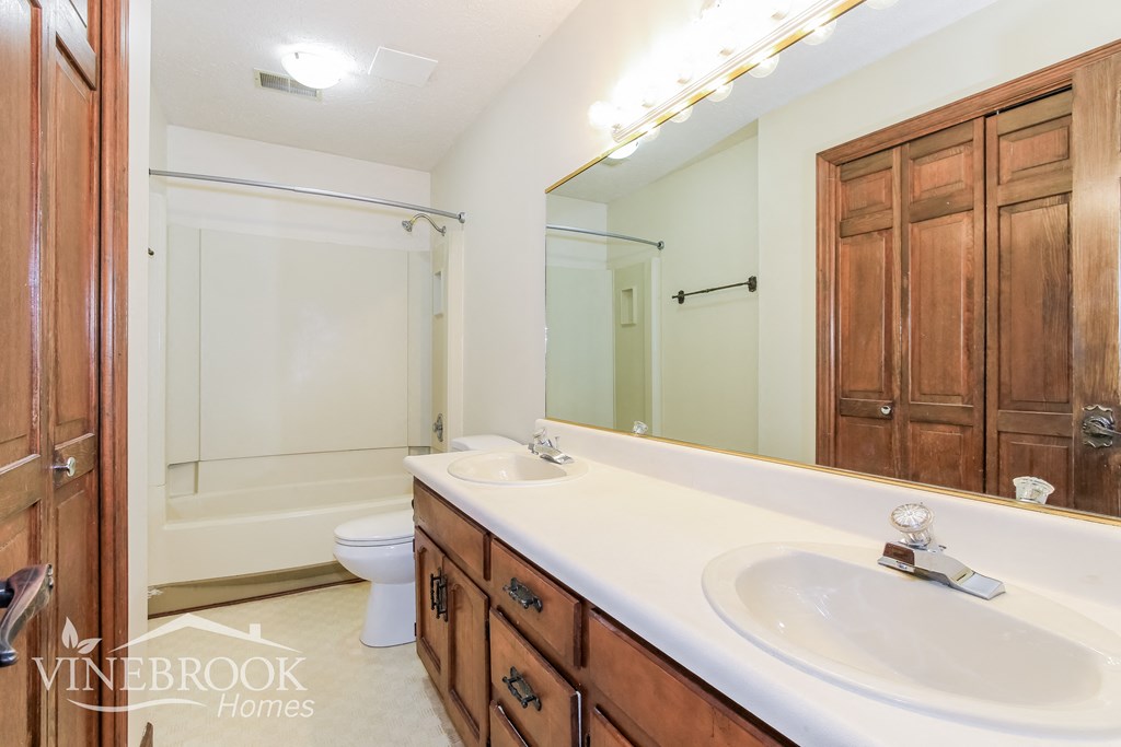 a bathroom with two sinks and a shower and a toilet
