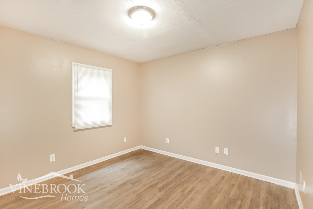 the upstairs bedroom with hardwood flooring and a window