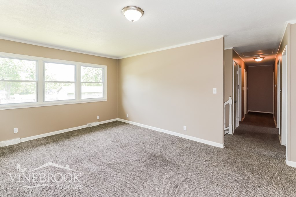 a master bedroom with carpeted flooring and a door to a hallway with a