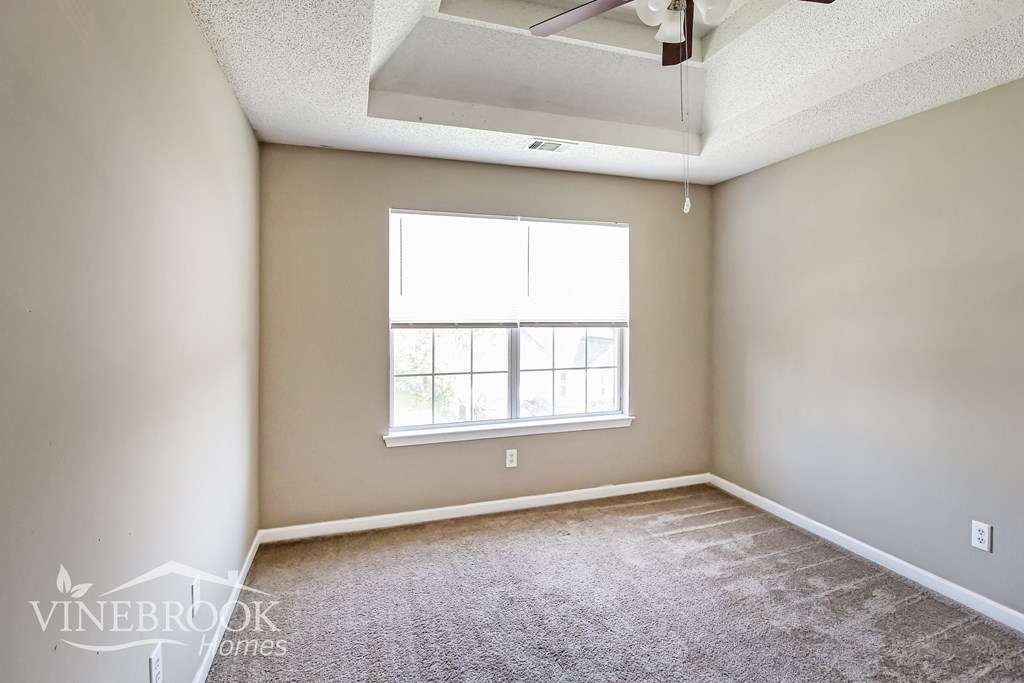 an empty room with a window and a ceiling fan
