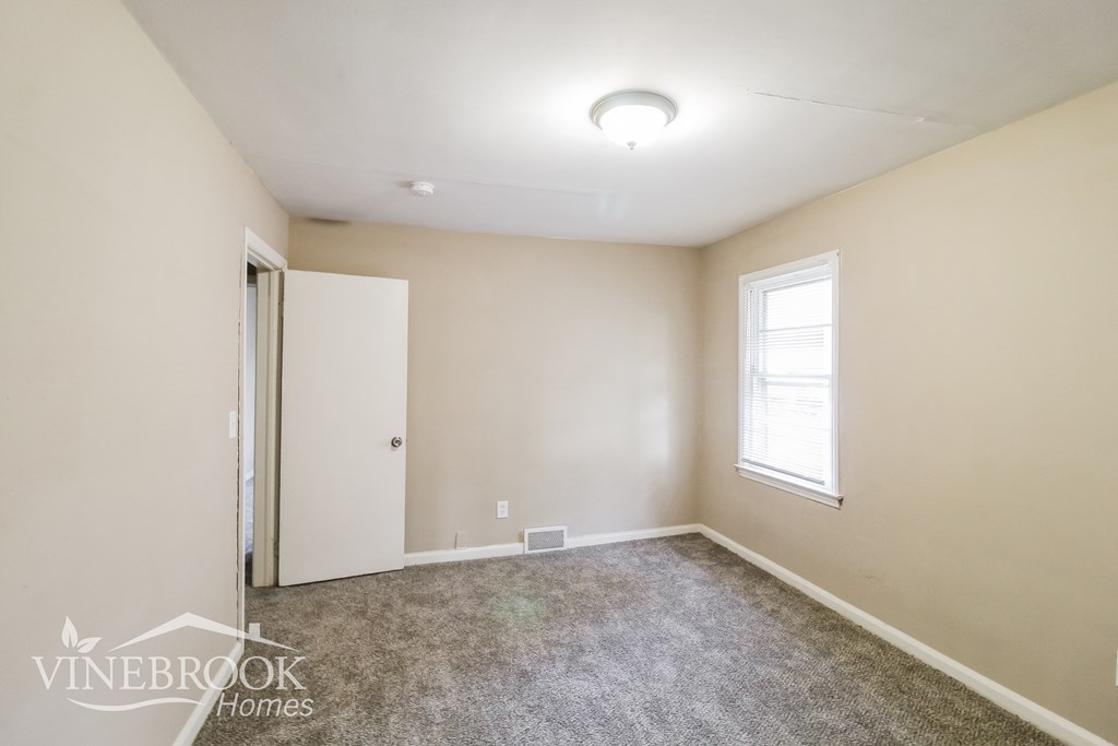 a bedroom with a carpeted floor and a door to a closet