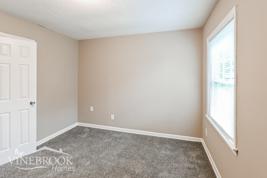 a bedroom with a carpeted floor and a white door