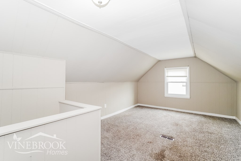 a white attic room with carpet and a window