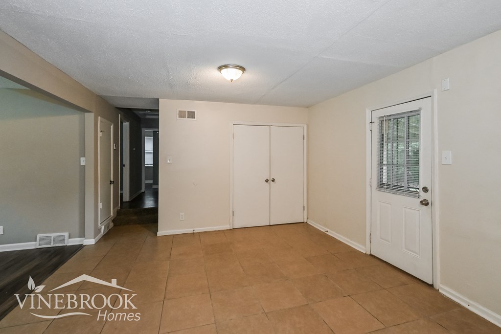 the living room of an apartment with a tile floor and a white door