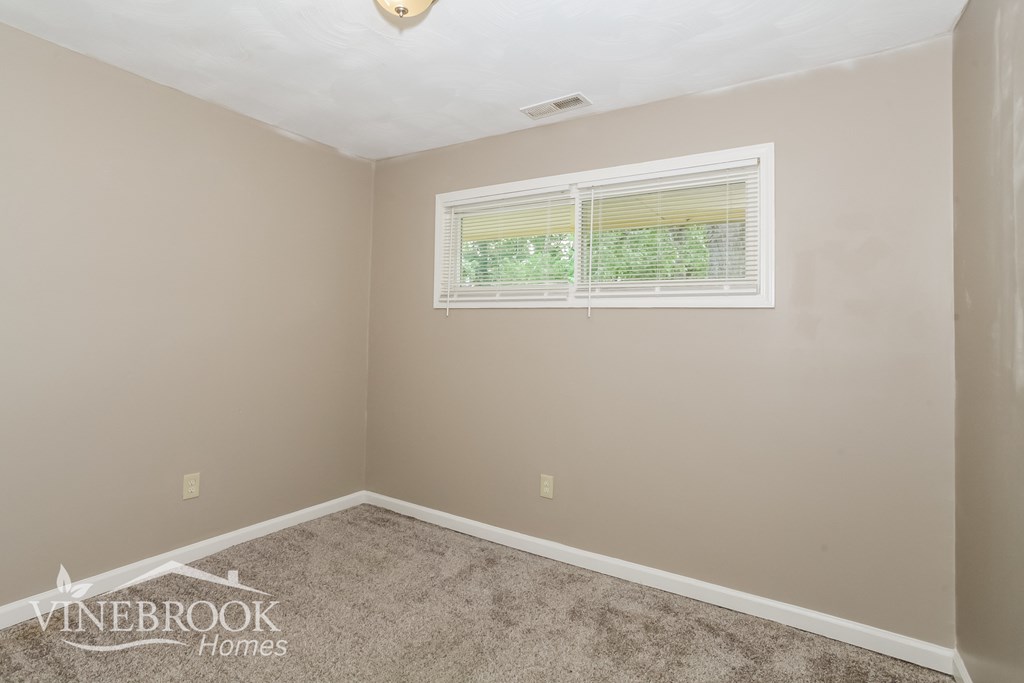 the bedroom of a home with carpet and a window