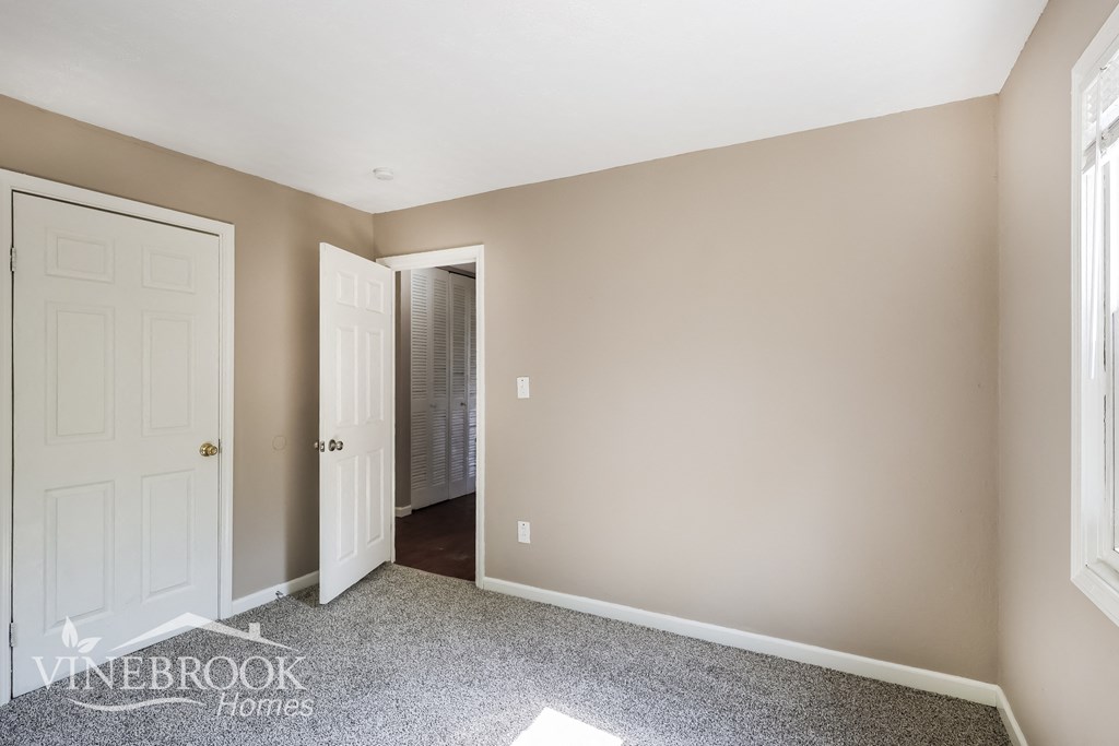 a bedroom with a closet and a white door and a door to a bathroom