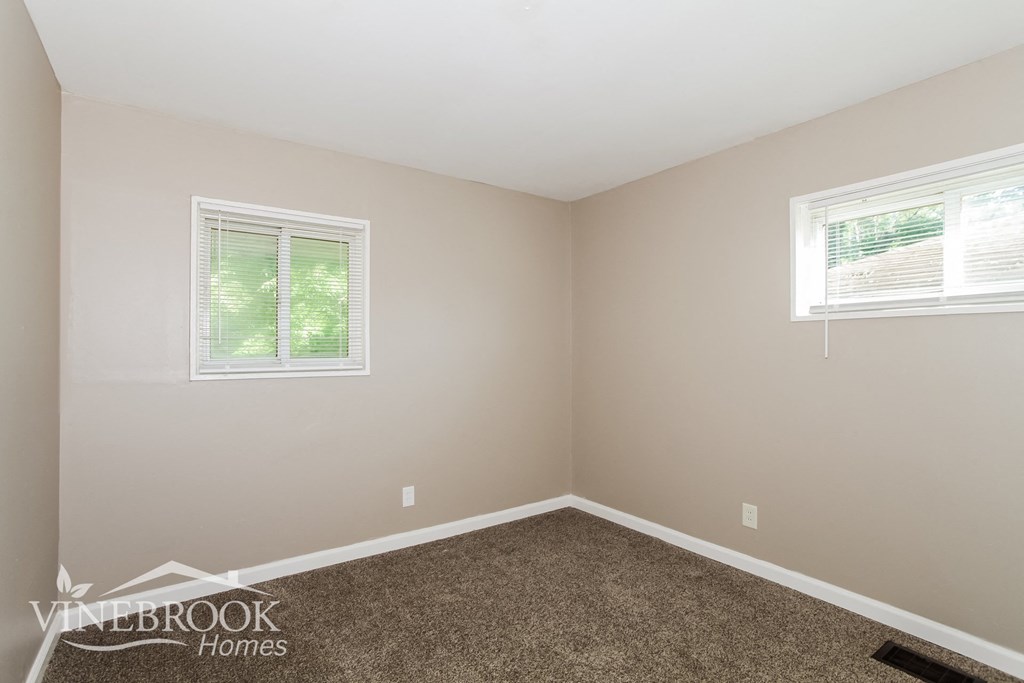 the bedroom of a home with carpet and two windows