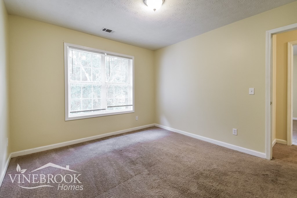 the living room of a house with carpet and a window
