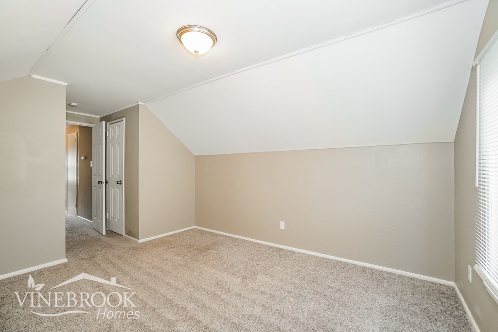 a bedroom with a carpeted floor and a door to a closet
