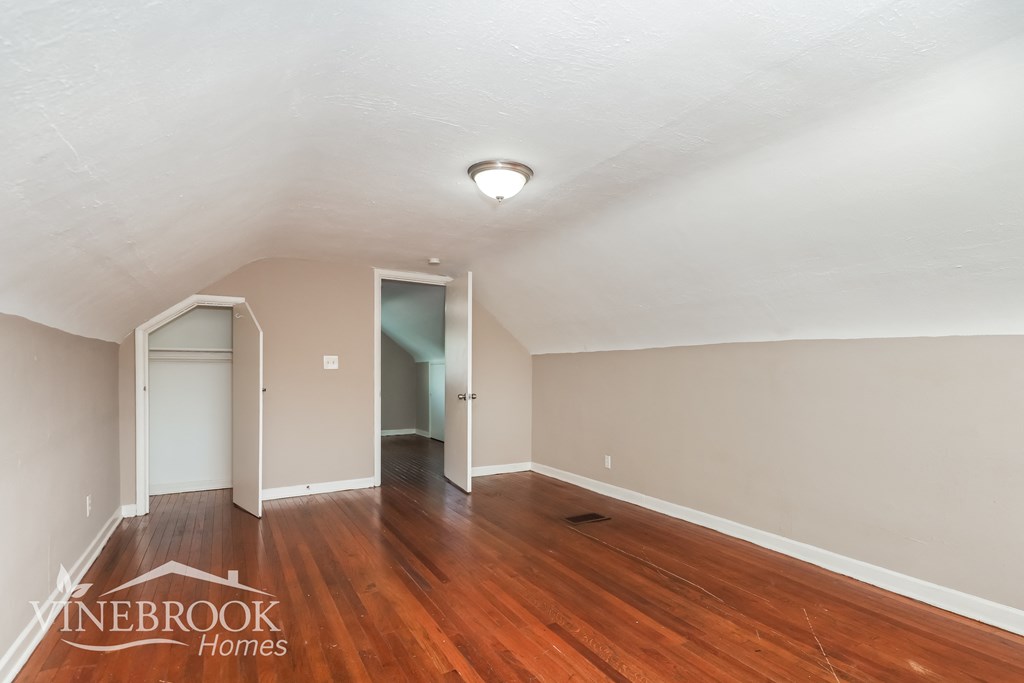 the living room of a home with wood flooring and a door to the hallway