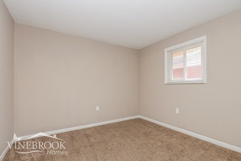 the living room of a home with beige carpet and a window