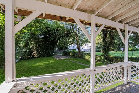 A wooden deck with a lattice fence overlooking a green lawn.