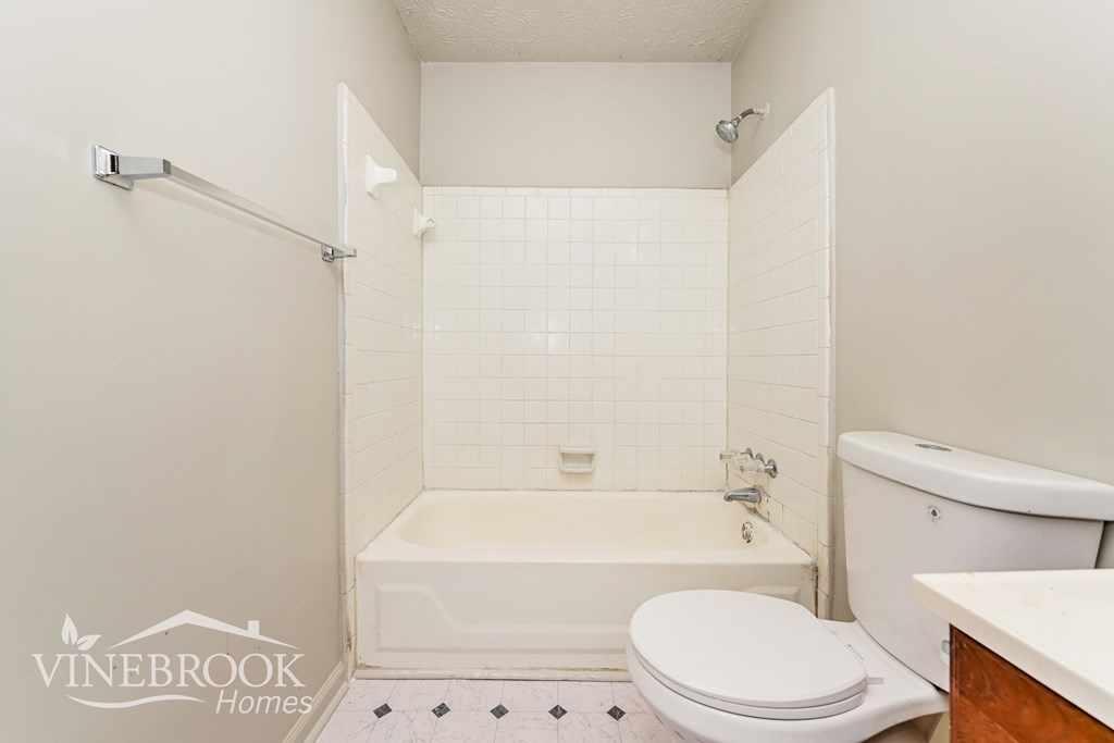a white bathroom with a tub and a toilet and a sink