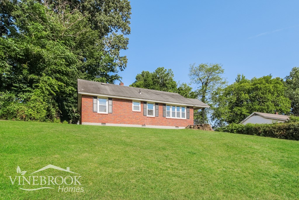 a small brick house on the top of a grassy hill