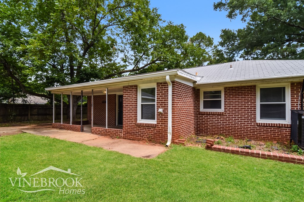 the front of a brick house with a lawn and a porch