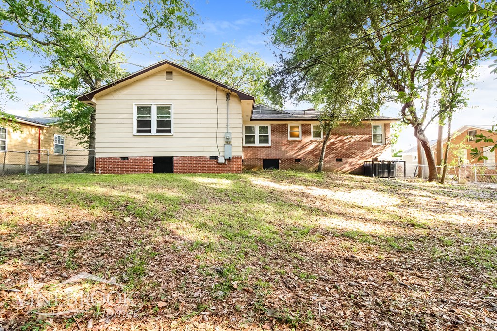 A house with a fence and trees in front of it.