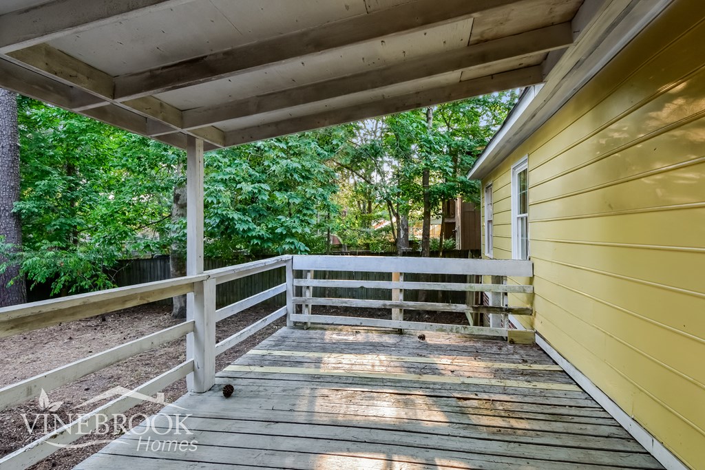 the porch of a yellow house with trees in the background