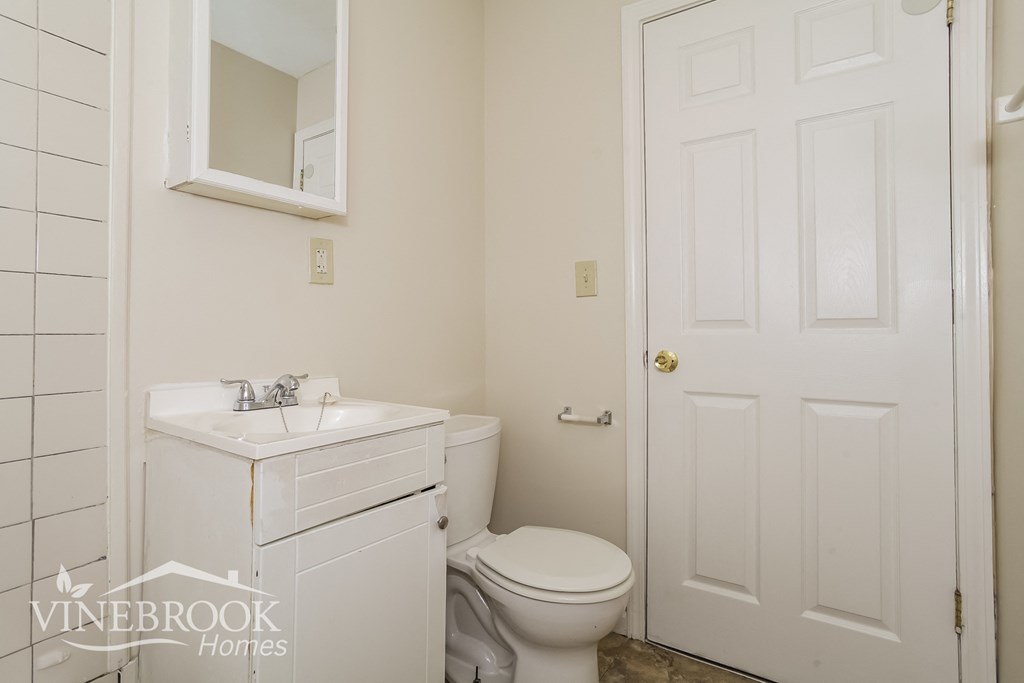 a white bathroom with a toilet and a sink
