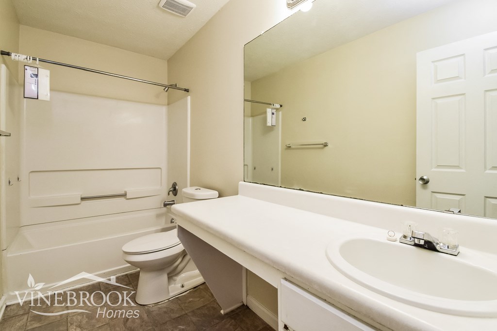 a bathroom with a large mirror and a sink and a toilet