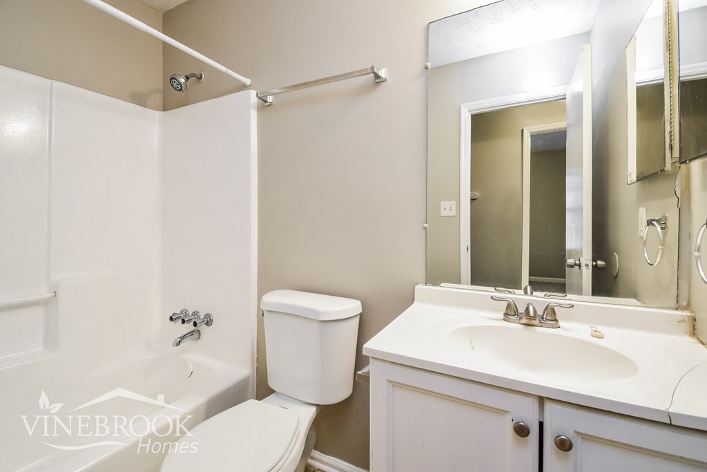a white bathroom with a white sink and toilet and a mirror