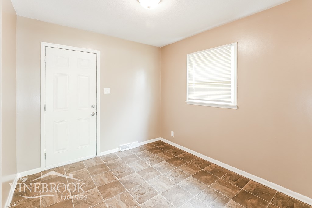 a room with a white door and a window and a tiled floor