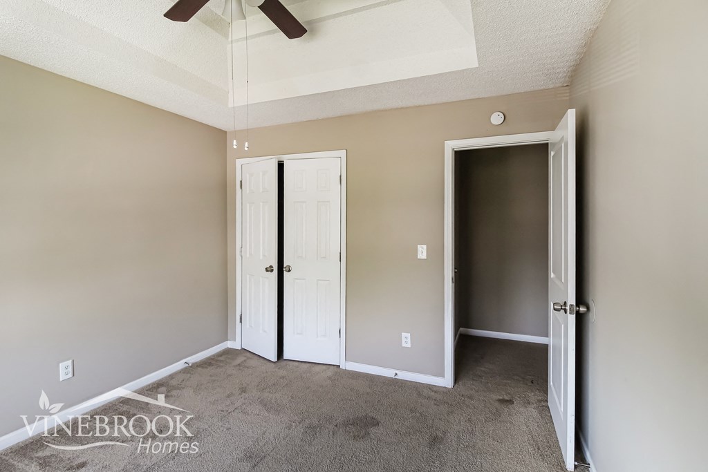 a bedroom with two doors and a carpeted floor and a ceiling fan