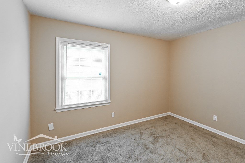 a bedroom with a carpeted floor and a window