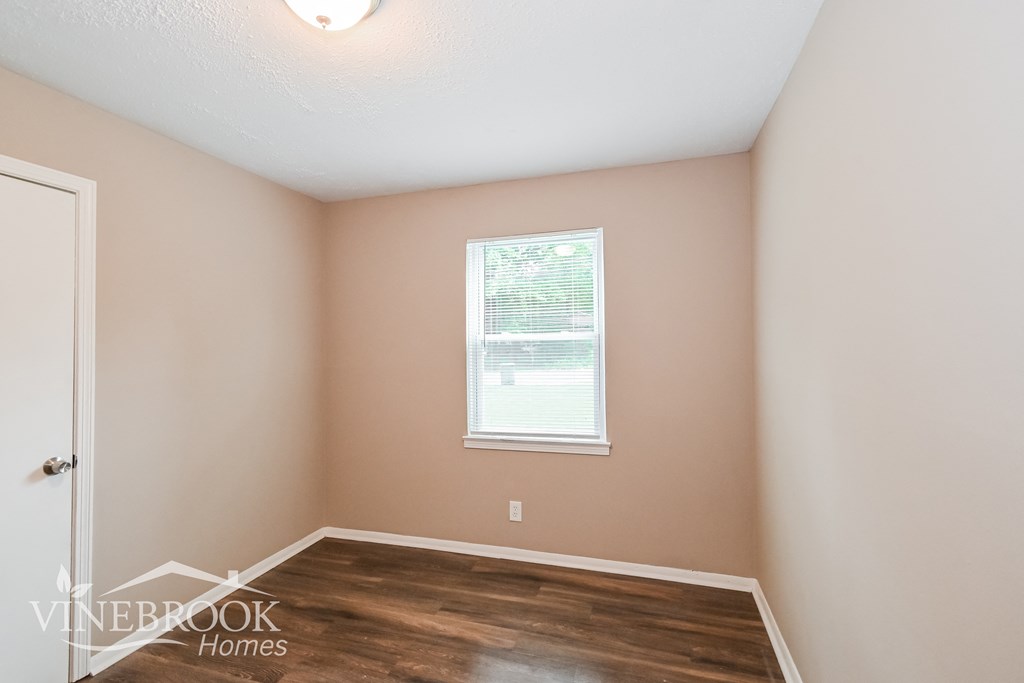 the living room of a home with a wooden floor and a window