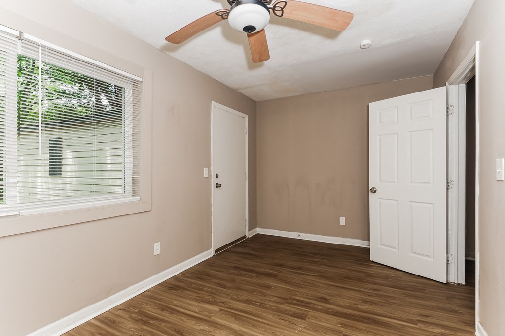 an empty bedroom with a ceiling fan and a window