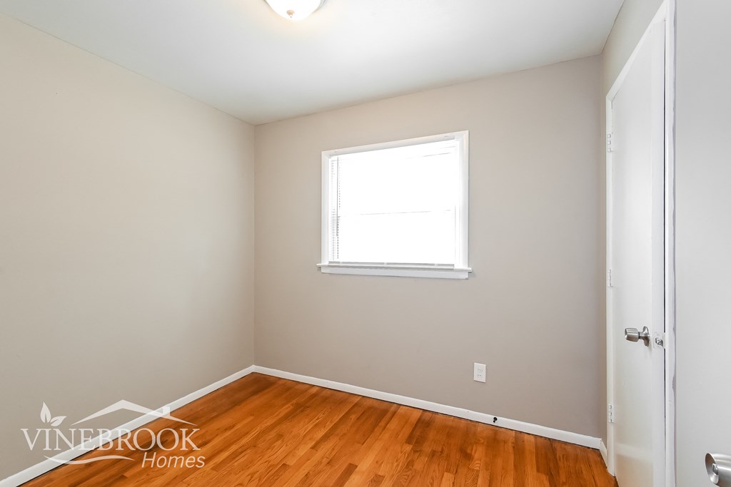 a bedroom with wood flooring and a window