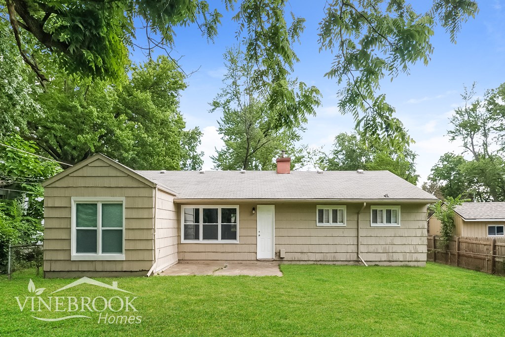 a small tan house with a yard and some trees