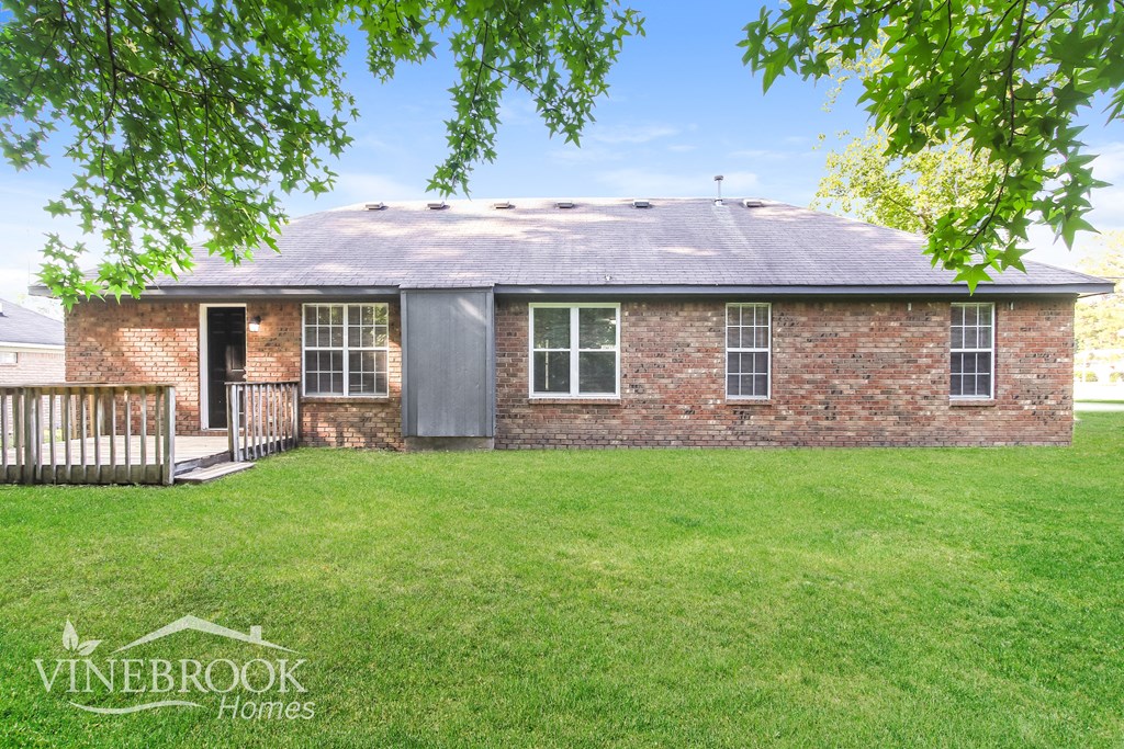 a small brick house with a yard and a deck