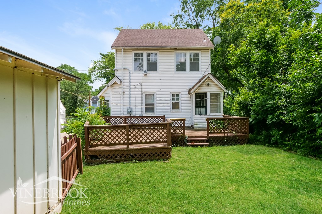 a backyard with a white house and a wooden fence