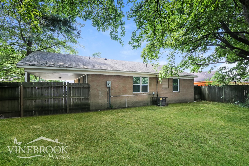 a backyard with a brick house and a fence