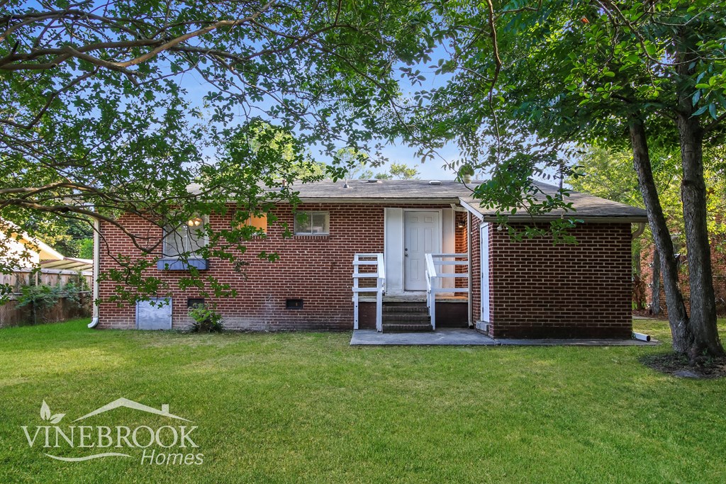 a small brick house with a porch and a tree