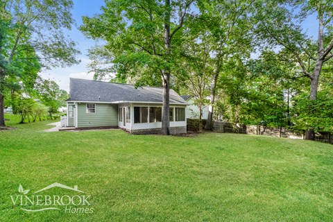 a small green house with a yard and trees