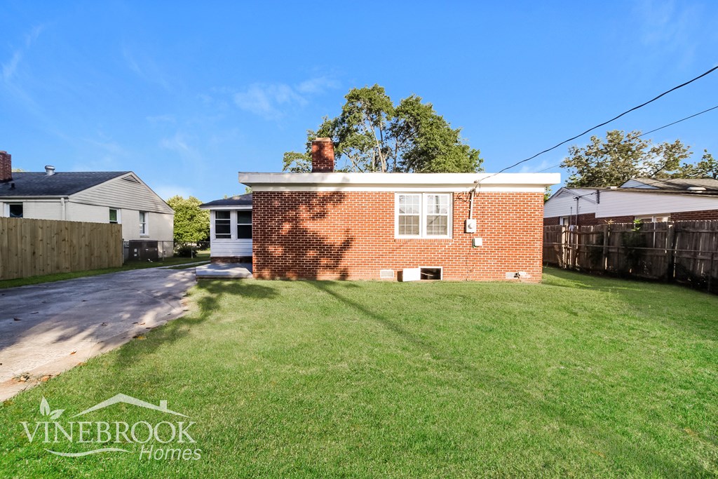 a small brick house with a lawn and a driveway