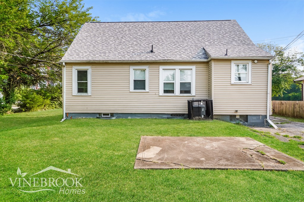 the back of a house with a yard and a dirt driveway