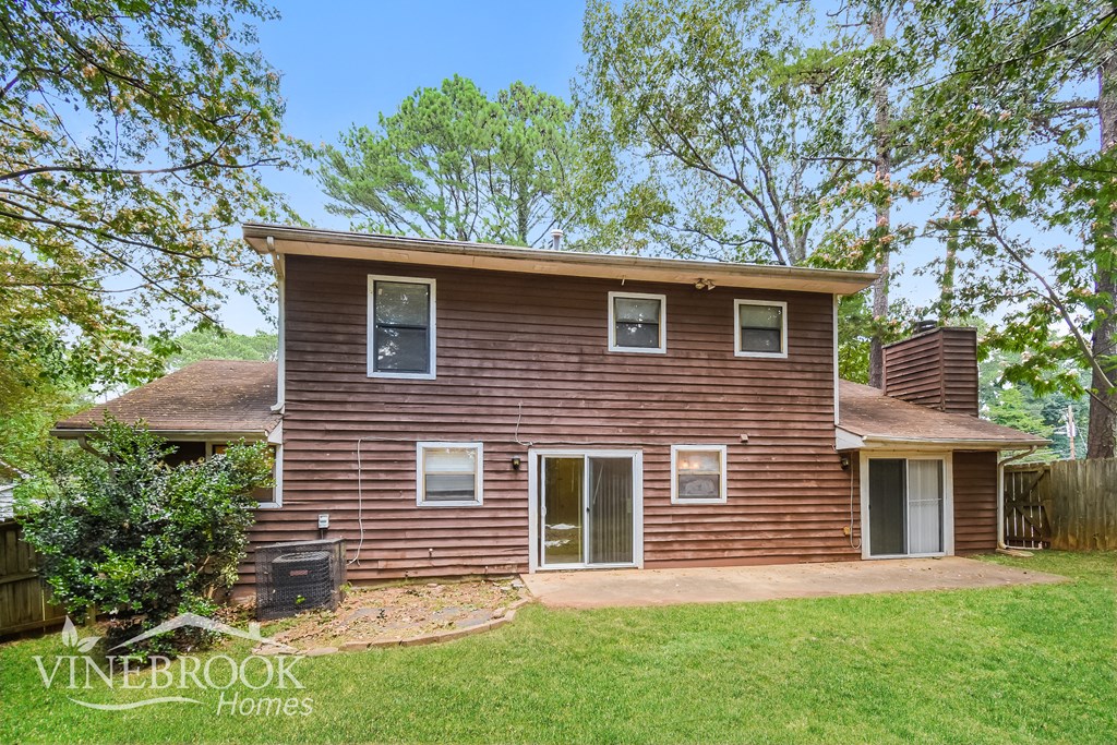 front view of a brown house with a yard and trees