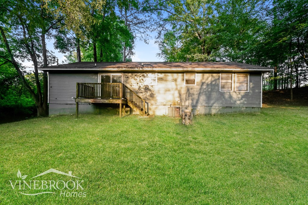 a small house in a grassy yard with a deck